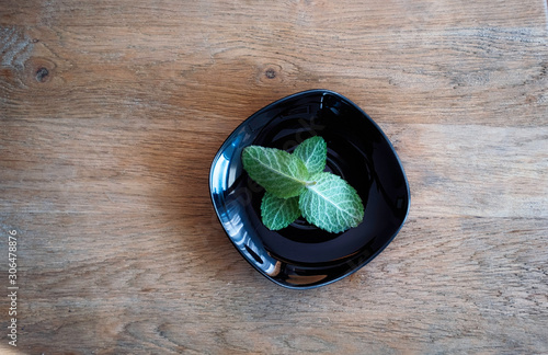 Fresh mint herb in a black plate on wooden background,natural tea ingredients.