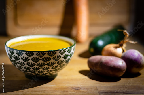 Bowl of vegetable soup with Vegetables around on wooden Background
