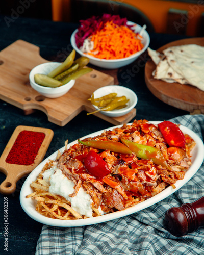 lamb doner kebab garnished with tomato and pepper, served with fries and yogurt