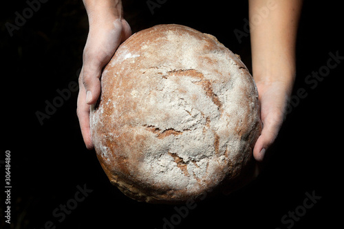 Hands holding fresh round bread.