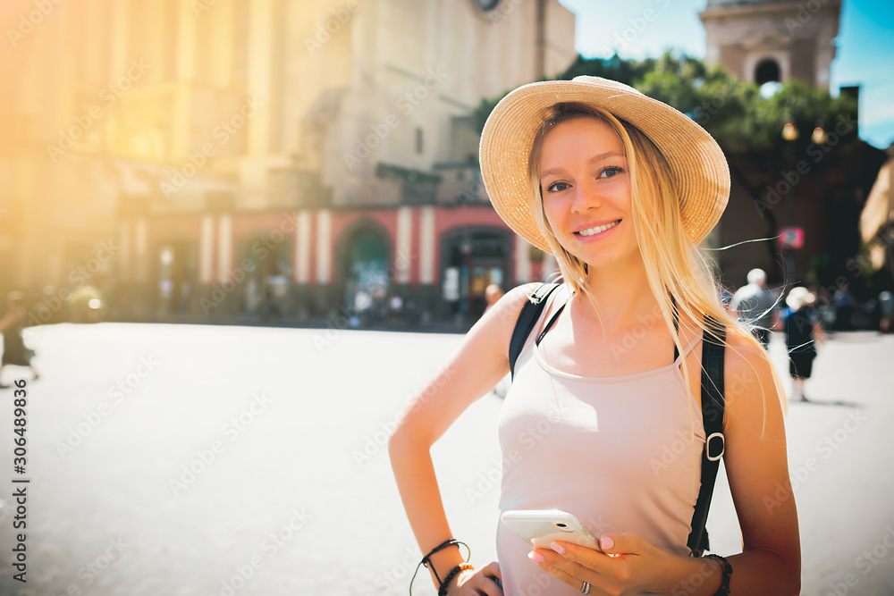 Europe travel summer tourism holiday vacation background - young attractive Caucasian smiling beautiful blonde girl face with hat mobile cell phone and using backpack in hand having chat connection