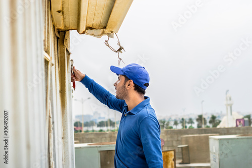 a professional carpenter man is fixing labor accommodation on the roof top and wearing blue color of uniform and white cap