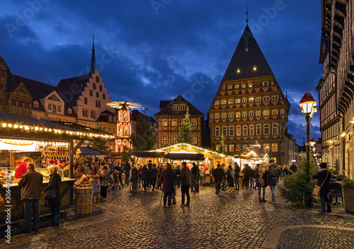 Hildesheim, Germany. Christmas market at Market Square in twilight on the picturesque backdrop of Roland House with stepped gable and adjacent half-timbered Bakers' Guild Hall and Butchers' Guild Hall