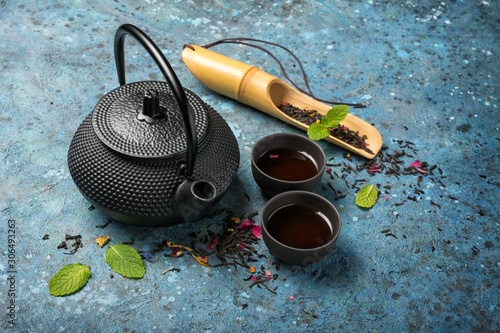 Black japanese cast iron teapot and dry tea in bamboo scoop with mint