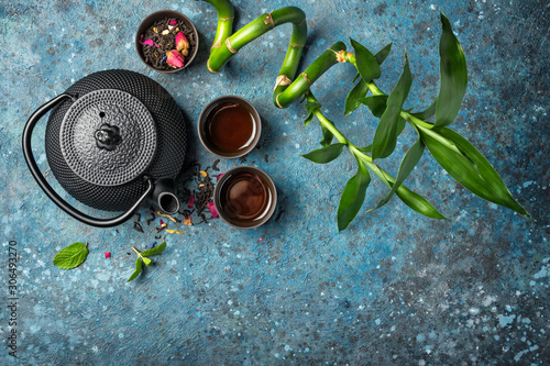 Black japanese cast iron teapot with rose tea, mint and green bamboo