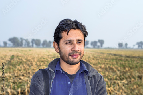 a happy farmer is standing at his cultivated rise fields and smiling 