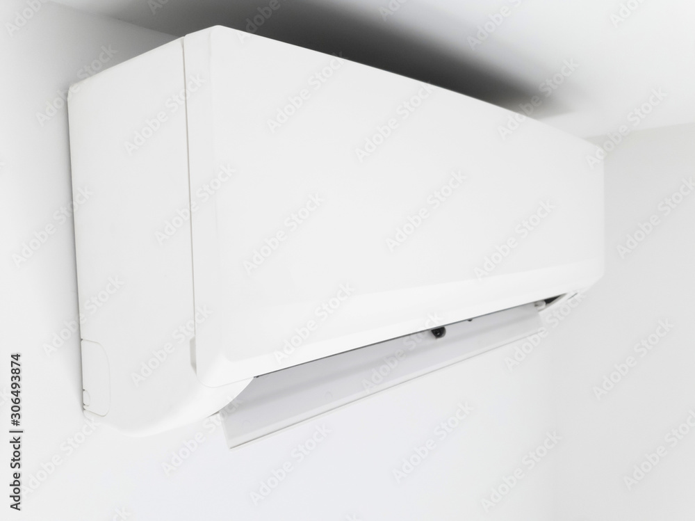 Modern air condition unit on a white wall inside the living room. Modern air condition unit on a white wall inside the living room.