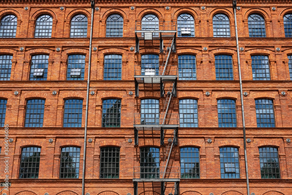 Red brick classic industrial building facade with multiple windows background. 
