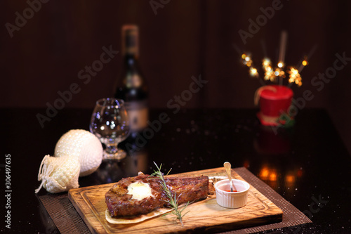 Rib eye steak at the christmas table. Steak rib eye roast on a wooden board with sauce and salt. Beef steak on wooden plate.