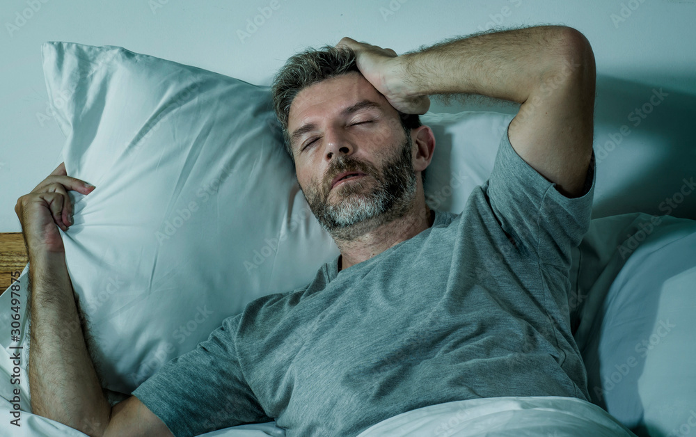 Fototapeta premium young sad and depressed man lying thoughtful and pensive on bed looking away feeling lost thinking suffering some problem in sadness emotion and depression concept