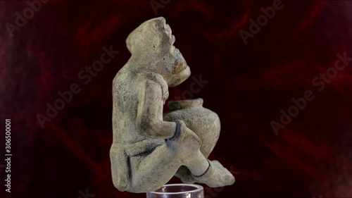 Ancient figure of a seated African with earrings in his ears and a jug. The work is made of porous stone.