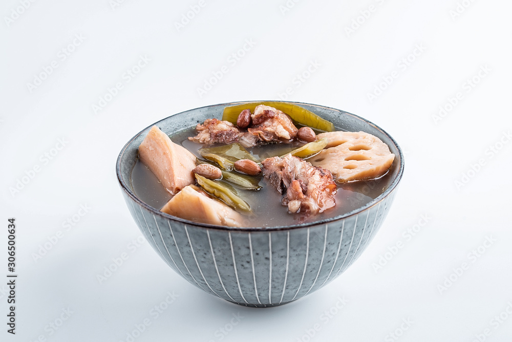 Nutritious delicious lotus root peanut pork bone soup in a bowl on white background