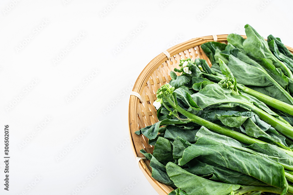 Bamboo sieve filled with fresh green vegetables kale hearts on white background Bamboo sieve filled with fresh green vegetables kale hearts on white background
