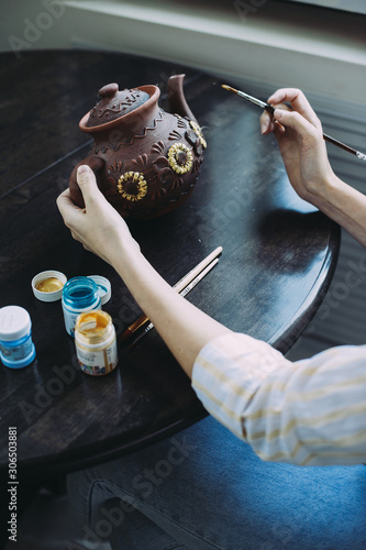 woman master paints the dishes at the workshop. clay teapot. handwork. Studio. design