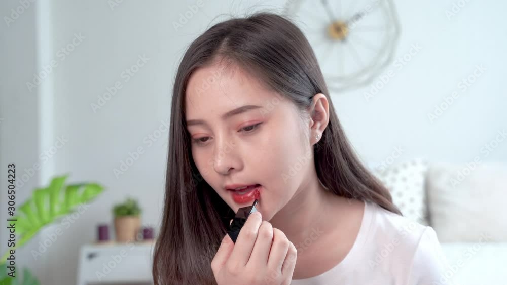Beautiful Asian women make up themselves by using a brush to apply lipstick to their lips. Beautiful Asian women make up themselves by using a brush to apply lipstick to their lips.