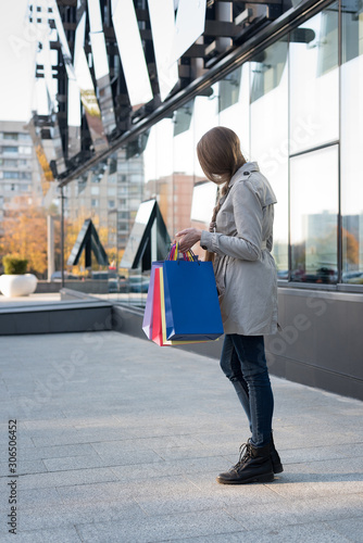 Young woman with colorful bags near mall. Shopaholic