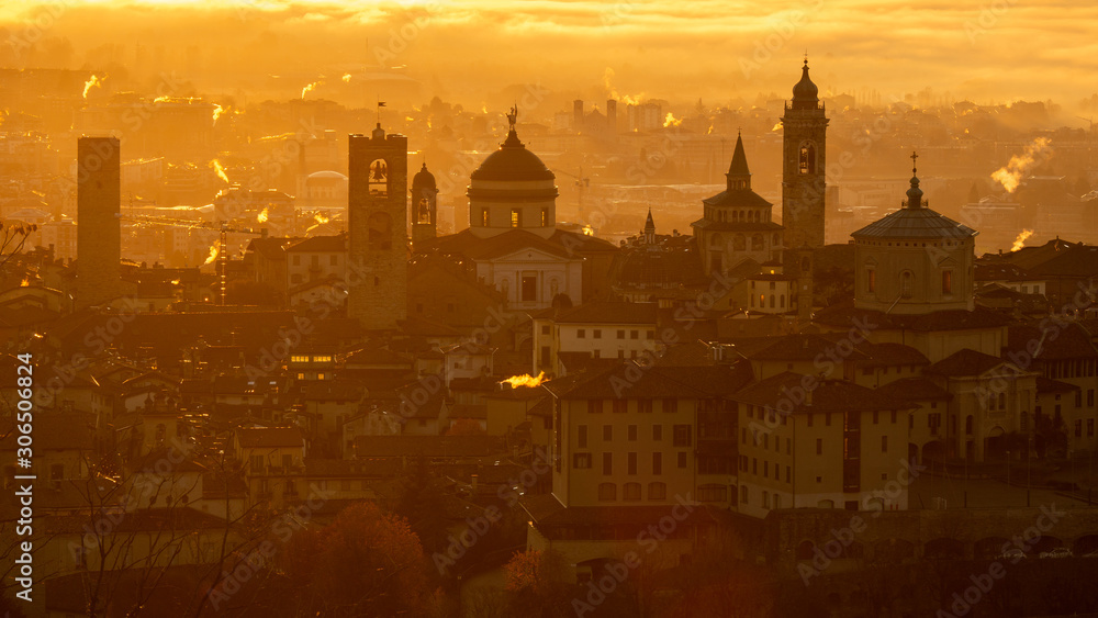 Bergamo, one of the most beautiful city in Italy. Amazing landscape at the old town during the sunrise. The fog covers the plain around the town. Fall season. Warm colors contest