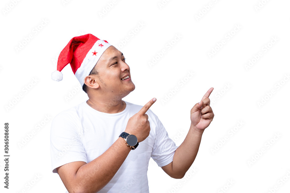 portrait of handsome casual asian man wear red santa hat raise his arm and pointing up to copy space portrait of handsome casual asian man wear red santa hat raise his arm and pointing up to copy space