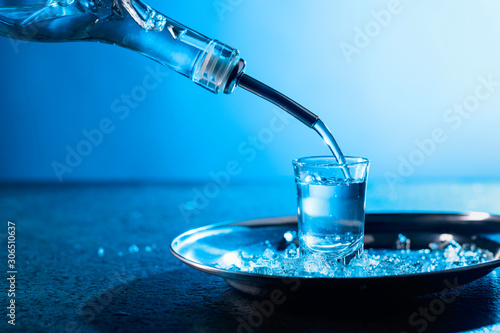 Vodka poured into a glass lit with blue backlight.
