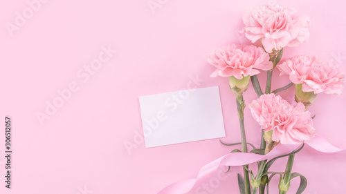 Beautiful, fresh elegant carnation flower bouquet with white greeting thanks gift card isolated on bright pink color background, top view, flat lay concept.