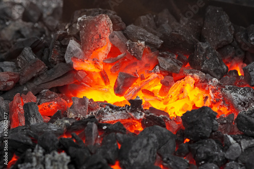 Embers glow in a iron forge, close view. Fire, heat, coal and ash.