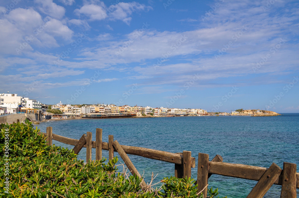 Mesmerizing view of the coastal town of the island Crete from the bushes and a wooden fencing