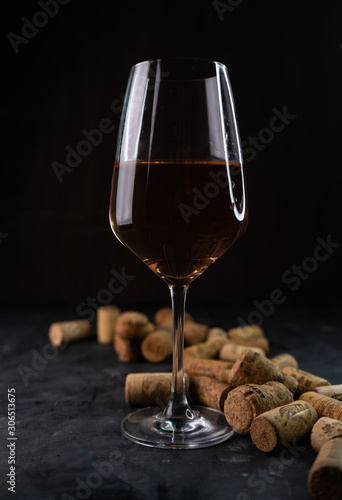 a glass of red wine with bottle caps