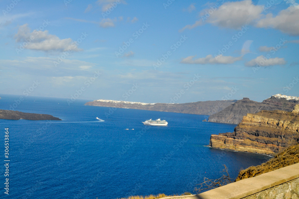 A cruise liner is sailing to the island with the volcano on Santorini