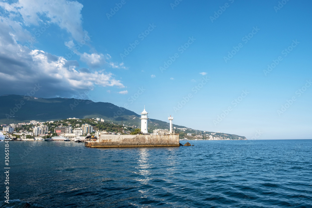 The white lighthouse tower at the entrance to the seaport of Yalta.