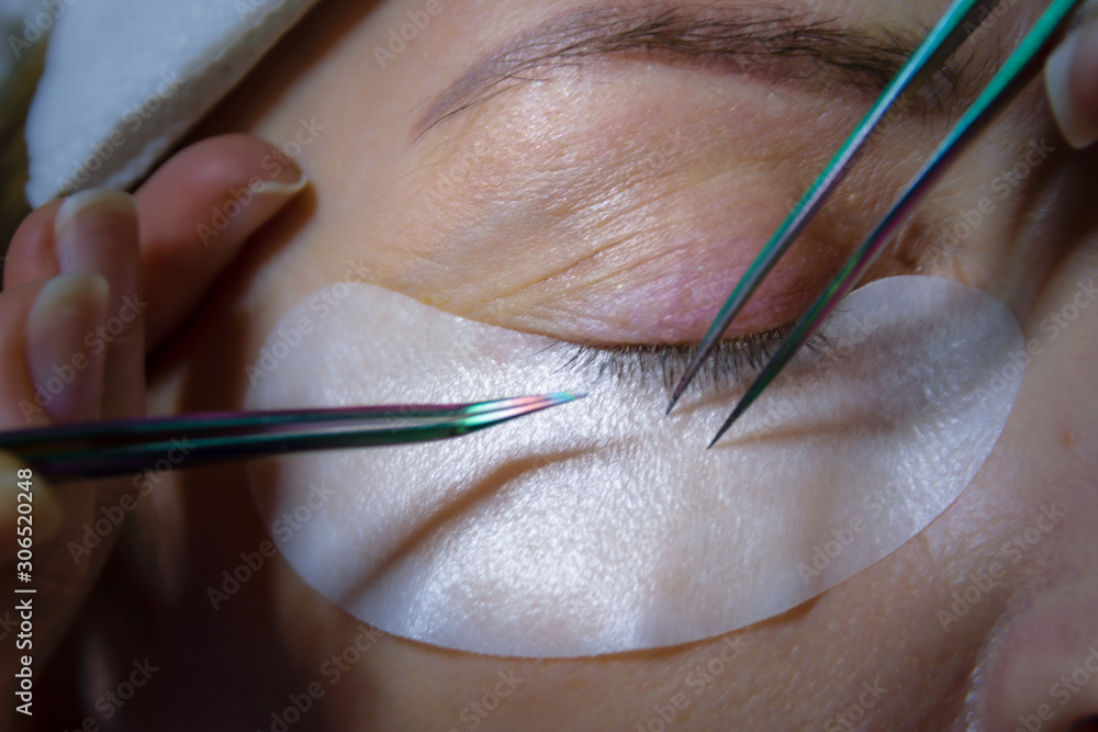 Woman eye with long black eyelashes. Eyelash extension procedure. Woman eye with long black eyelashes. Eyelash extension procedure.