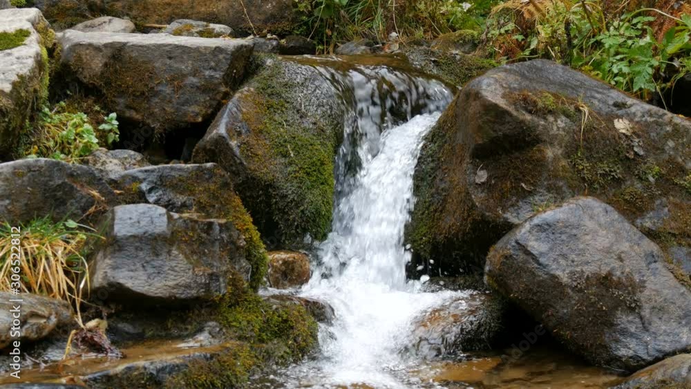 Large massive black stones on which water flows from a mountain transparent stream Large massive black stones on which water flows from a mountain transparent stream