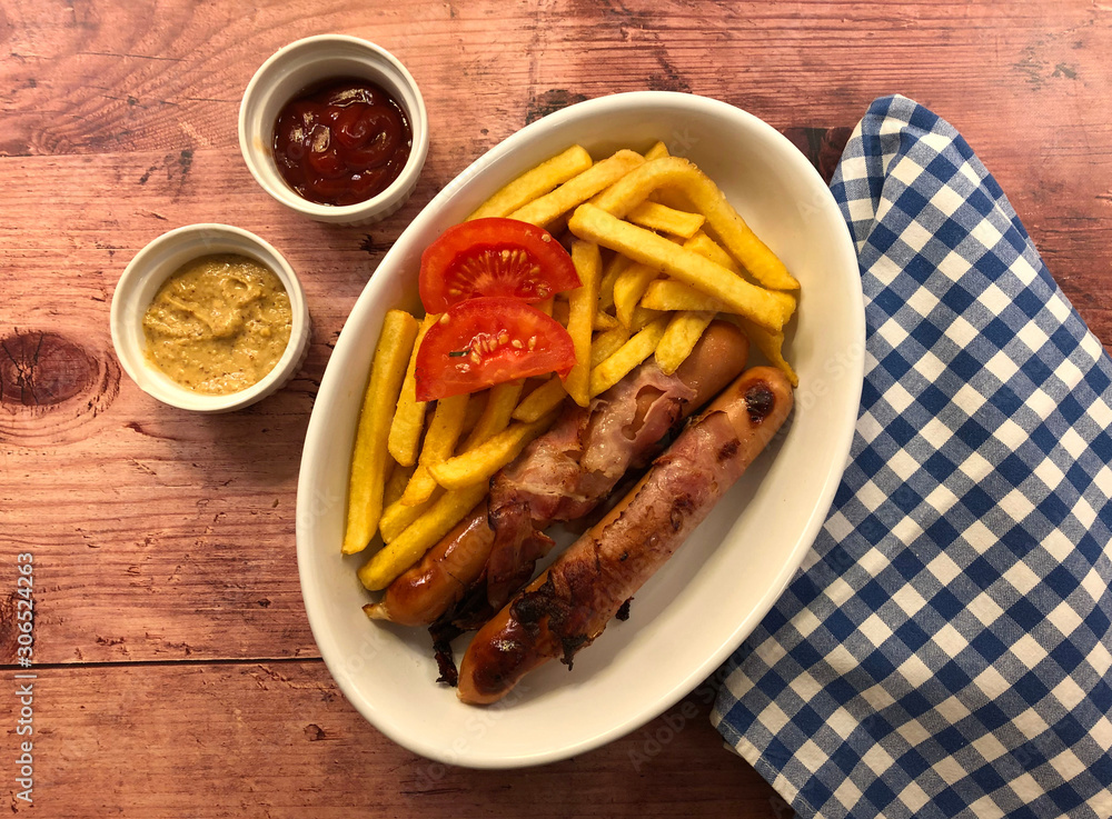 Bacon wrapped sausages with french fries and dip. Hearty meal concept. Bacon wrapped sausages with french fries and dip. Hearty meal concept.