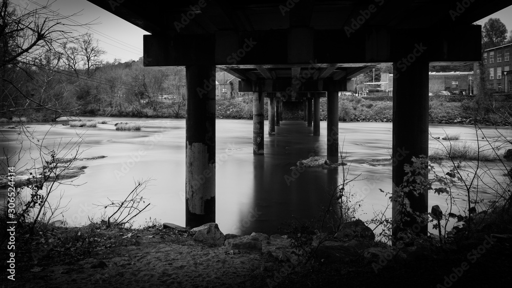 Under the highway bridge spanning a  river with smooth water