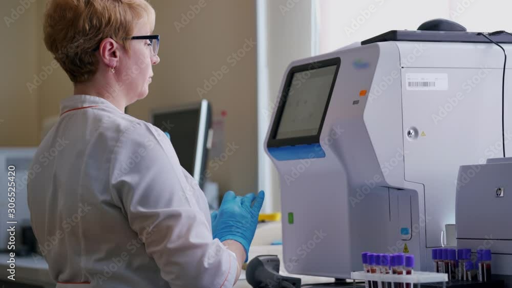 Laboratory worker in a modern microbiology cabinet. Side view of a female in medical uniform working on a special equipment for testing blood samples in research laboratory.