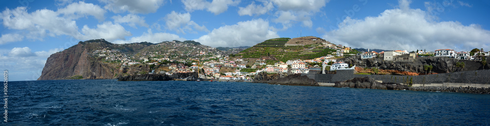Wide panoramic view of Madeira island. Ocean, cliff and mountains with blue skies and clouds in background