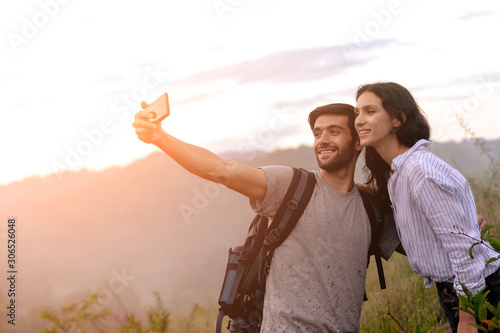 Couple taking selfie photo with smart phone hiking on mountain.