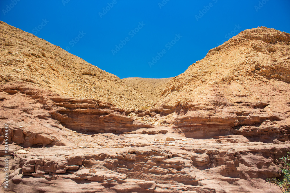 Israeli desert scenery dry landscape sand stone rocks wallpaper background view with empty vivid blue sky 