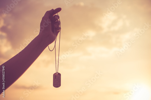 Women's is holding military dog tags in hand. Memories and sacrifices concept. photo