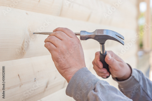 A man hammer and chisel hammer nails into a house of wood in the open air