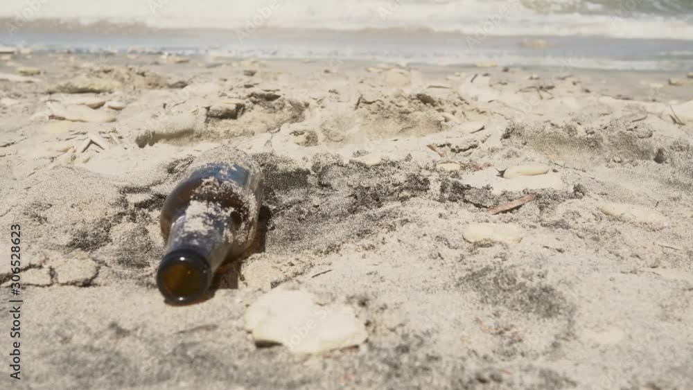 a beeer bottle become trash on the beach when someone abbandoned it a beeer bottle become trash on the beach when someone abbandoned it