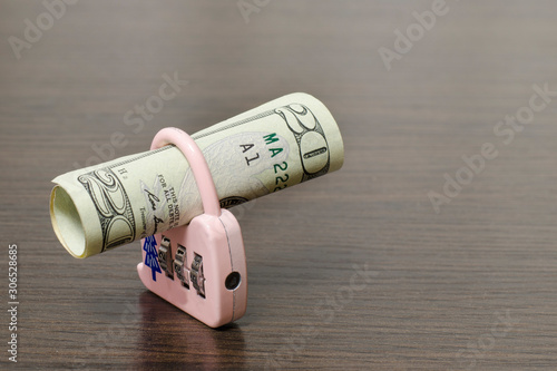 Rolled up banknote and lock. It is a symbol of economy and cash savings.