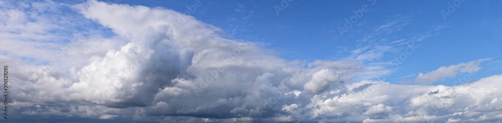 September is the autumn sky. White aerial clouds on a blue sky, panoramic photo.