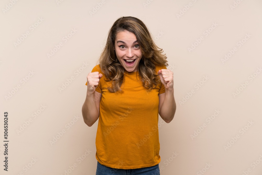 Young blonde girl over isolated background celebrating a victory in winner position Young blonde girl over isolated background celebrating a victory in winner position
