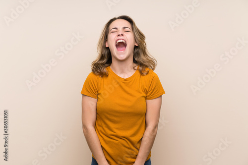 Young blonde girl over isolated background shouting to the front with mouth wide open