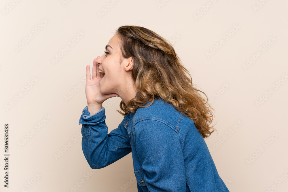 Young blonde woman over isolated background shouting with mouth wide open Young blonde woman over isolated background shouting with mouth wide open