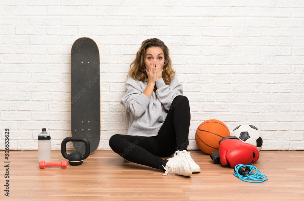 Young sport woman sitting on the floor with surprise facial expression