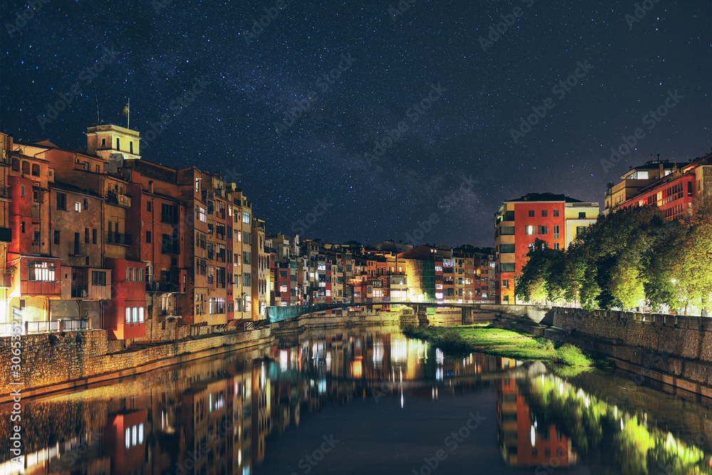 Night view of the Spanish city of Girona. old city lights, starry sky, colorful houses and the Onyar river.