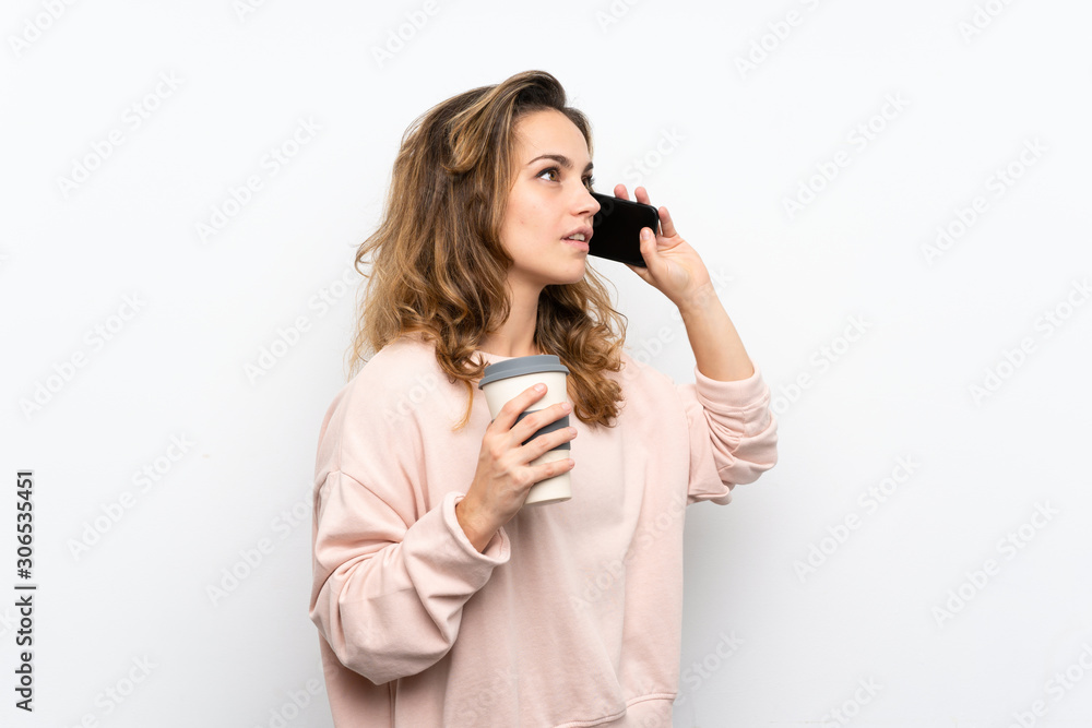 Young blonde woman holding coffee to take away and a mobile Young blonde woman holding coffee to take away and a mobile