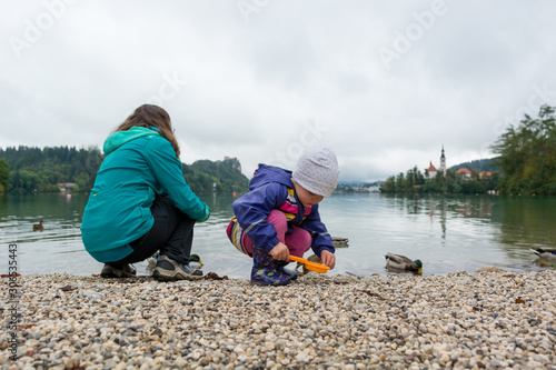Obraz na płótnie Mother and daughter playing on lake shore with romantic church in the bacground. w salonie