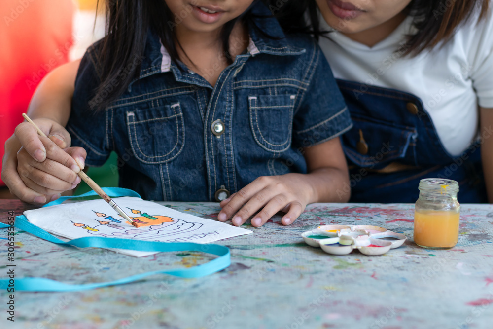 Fototapeta premium The mother and child are involved in creating watercolor artwork on cloth bags.